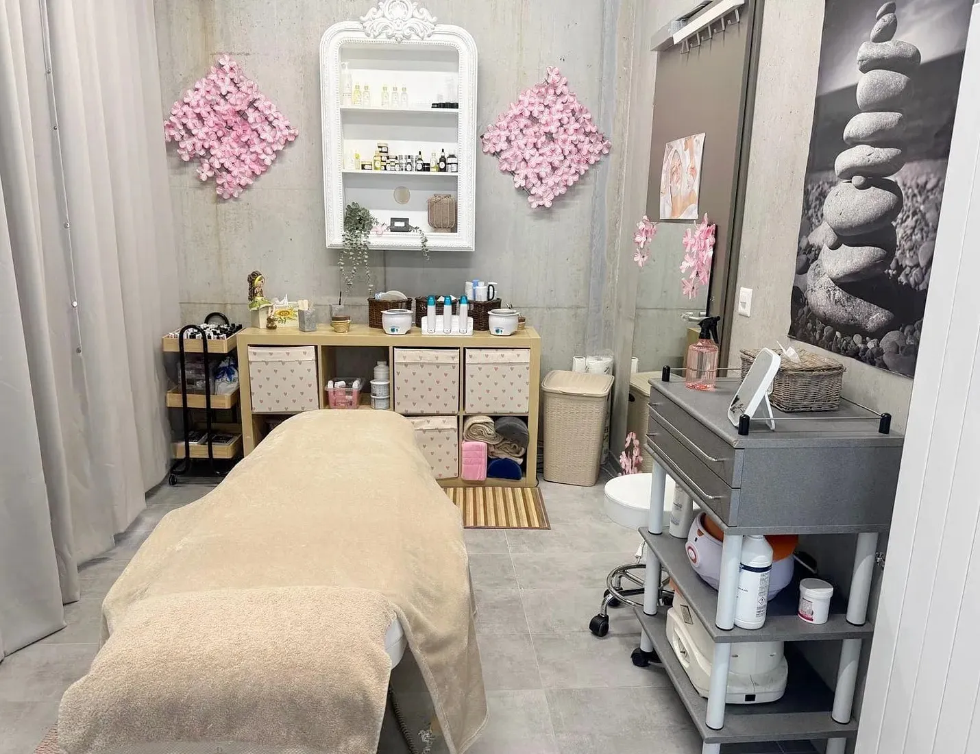 Cabine de soins : table couverte d'une serviette crème, murs en béton brut et fleurs de cerisier