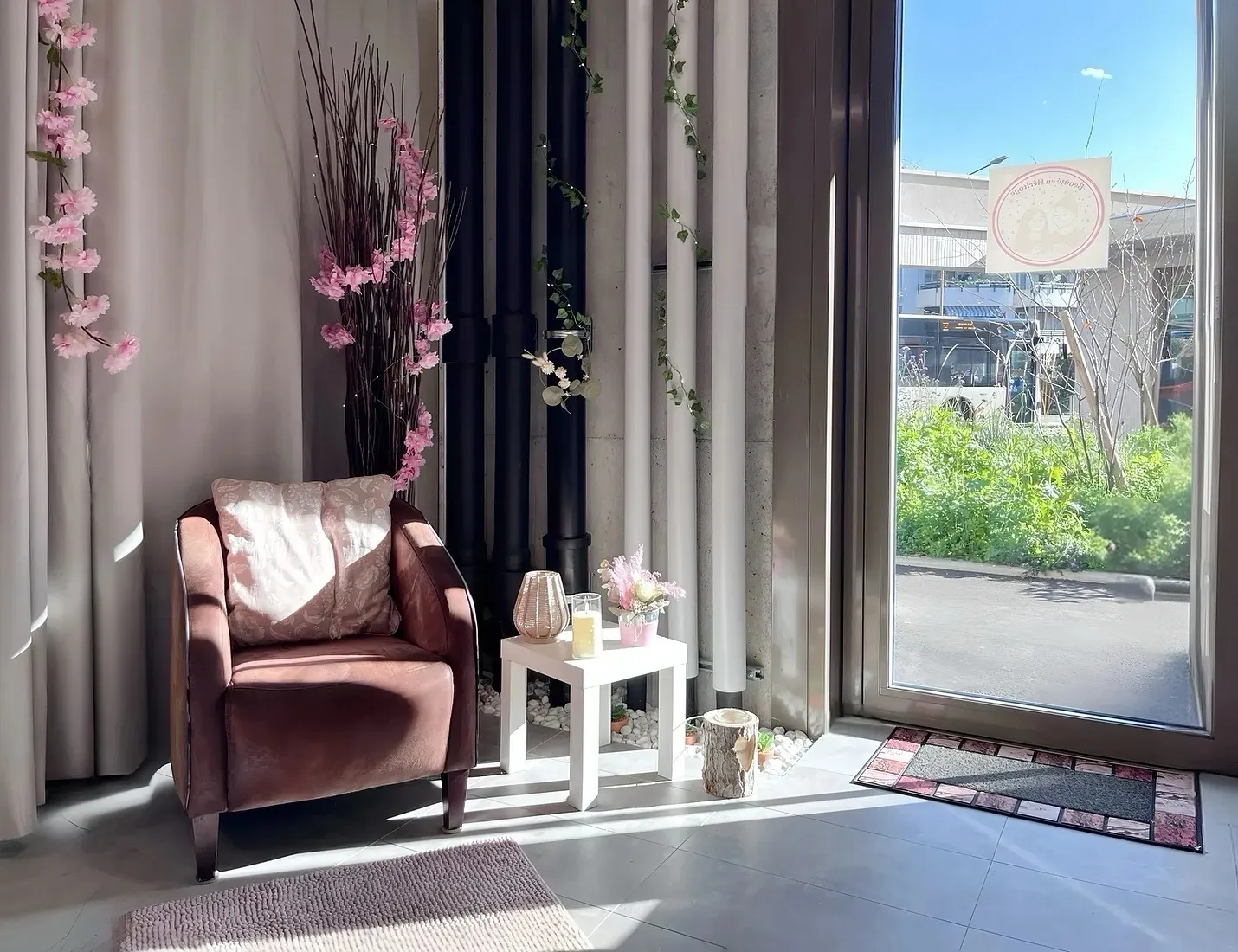 Le coin accueil de l'institut : fauteuil en velours rose, fleurs de cerisier et lumière naturelle
